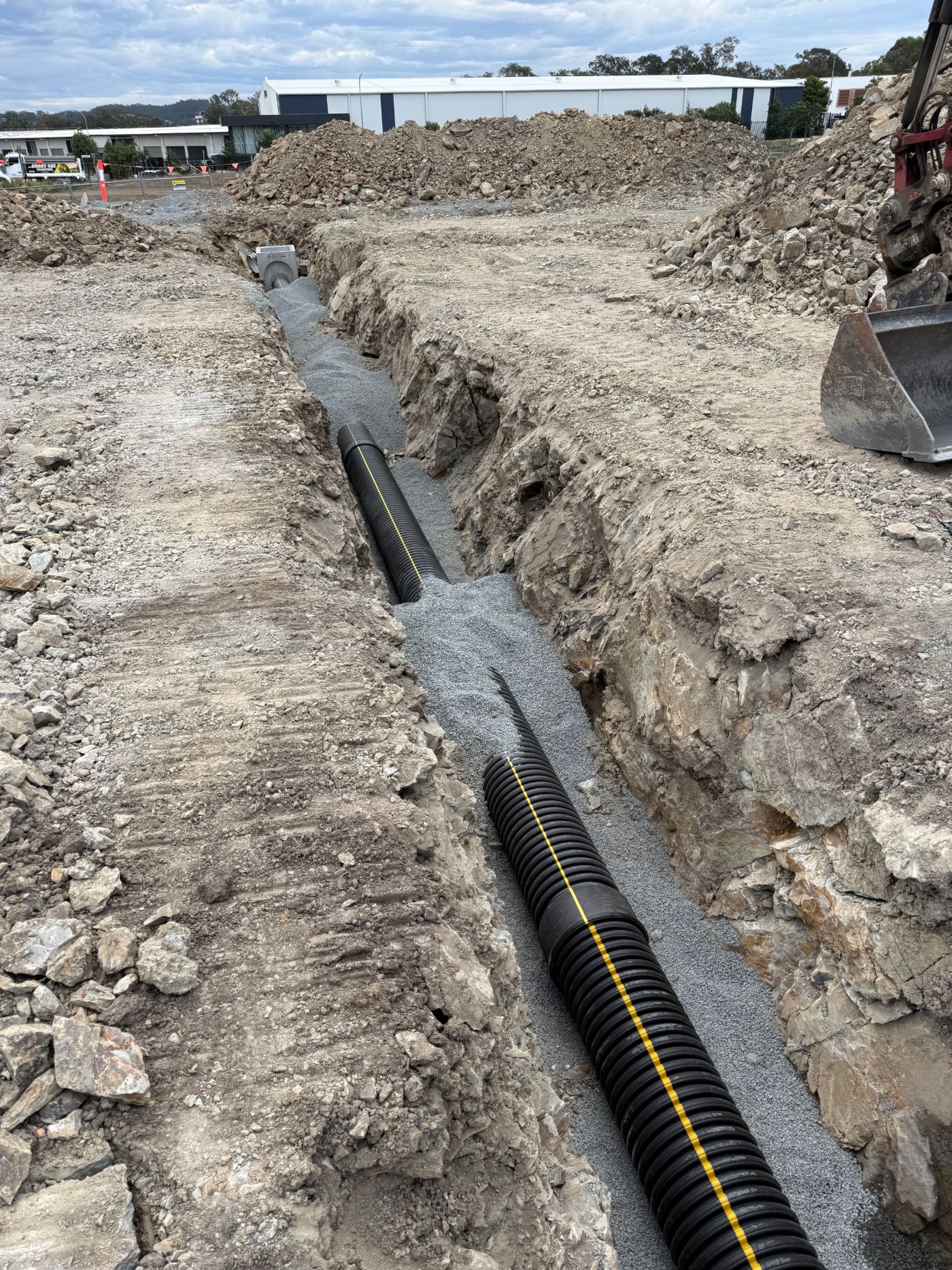Drainage line bedded in gravel through a rock trench