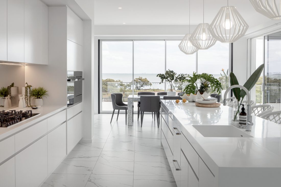 White kitchen with island sink opening to the dining room