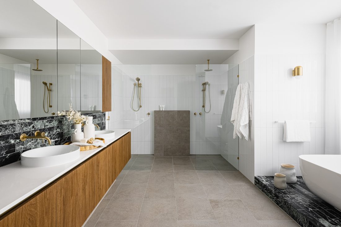 Double vanity with brushed brass tapware and twin walk-in showers