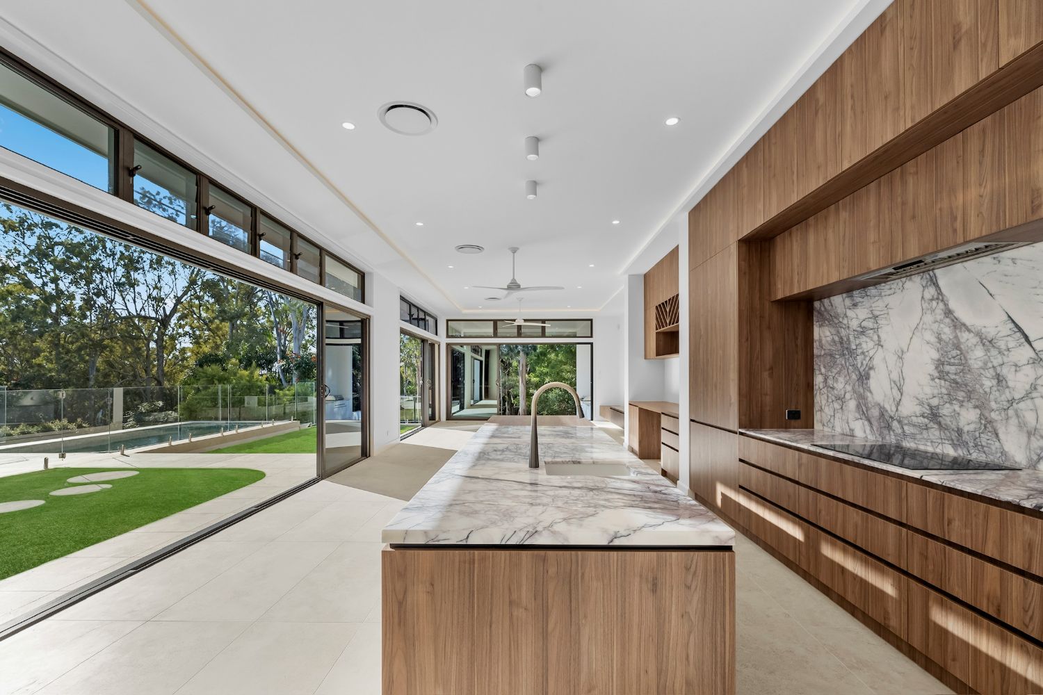 Open-plan kitchen with marble island and timber cabinetry opening to the garden